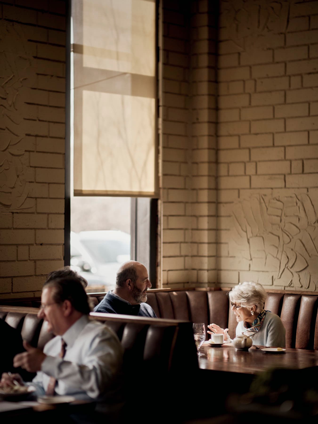 A couple sharing a window-lit corner booth against painted brick